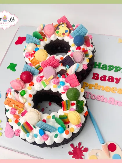 A bright and colorful number "8" cake for Princess Toshani. This cake is a candy explosion, topped with macarons, chocolates, and rainbow candies.