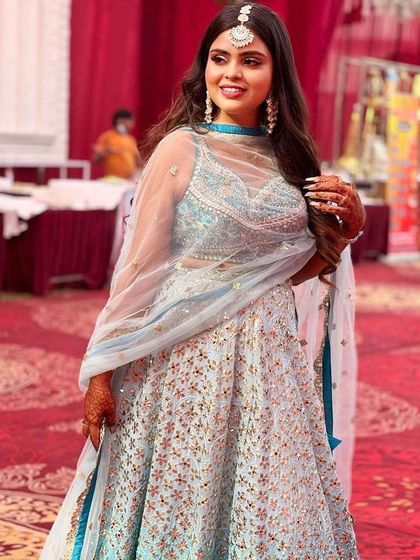 A smiling client looking lovely in her pastel blue rental lehenga. The sheer dupatta and illusion neckline on the blouse add a touch of modern elegance.