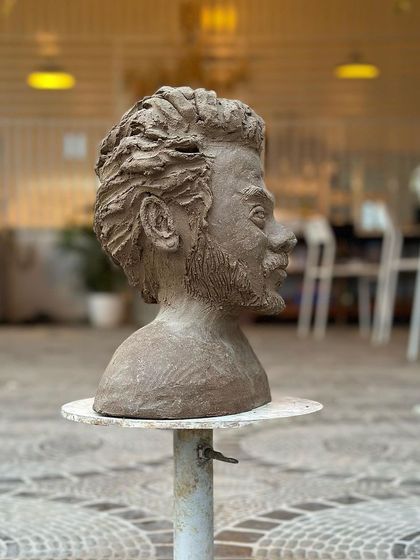 A side profile of a sculpted bust, capturing the likeness and emotion of the subject with remarkable detail.