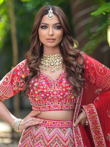 A powerful bridal pose in a multi-colored embroidered red lehenga. The look is completed with a broad Kundan necklace and a simple maang tikka.