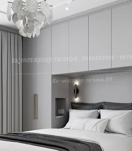 An elegant, monochromatic bedroom with light grey wardrobes that seamlessly blend into the wall. The statement chandelier and minimalist wall sconces add a touch of sophistication.
