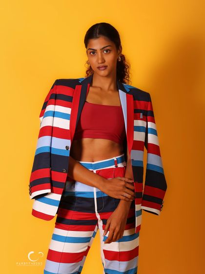A classic fashion portrait with the jacket draped over the shoulder. It's a chic and stylish look that highlights the red crop top underneath.