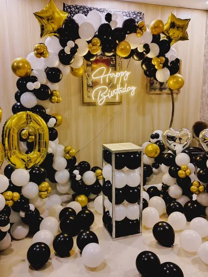 A classic black, white, and gold theme for a 60th birthday celebration. I used a balloon arch, large foil numbers, and a 'Happy Birthday' neon sign for this home setup.