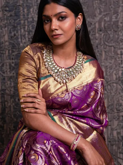 This model showcases a regal purple Kanchipuram silk saree, a color of royalty and sophistication, perfect for a bride's reception or engagement.