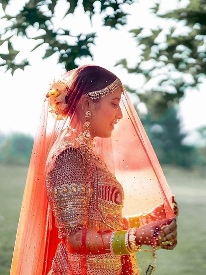 A soft, romantic portrait of the bride under her red veil. The delicate flowers in her hair and the intricate embroidery of her outfit create a timeless look.