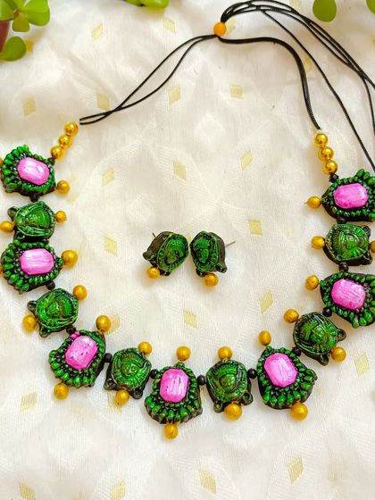 The same Durga motif choker, this time with pink stones. Offering color variations helps cater to different customer tastes during the festive season.