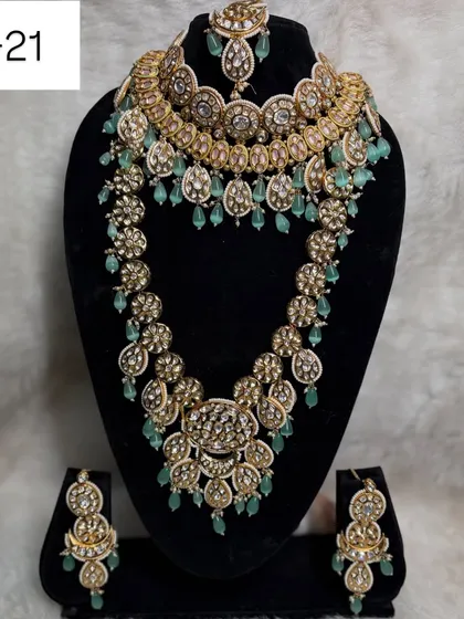 This modern layered set, code B-21, is a favorite among brides. It combines a statement choker with a matching long haar, featuring beautiful mint green beads for a fresh and contemporary look.