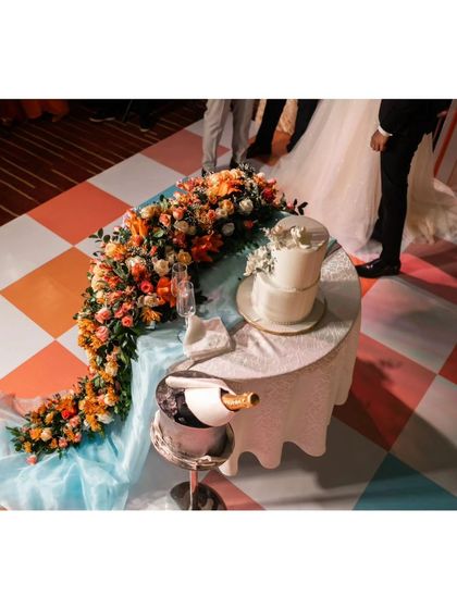 The wedding cake table, featuring a cascading floral arrangement in autumn colors that flows beautifully onto the checkered dance floor.