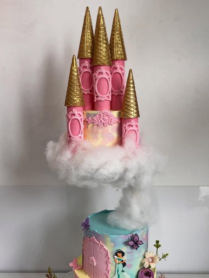 A close-up of the floating princess castle, showing the intricate details of the golden-tipped pink turrets resting on a fluffy cloud of edible cotton.