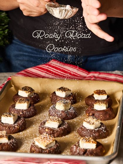 Dusting our Rocky Road Cookies with a little "snow" of powdered sugar. These cookies are a festive favourite, topped with a perfectly torched marshmallow.