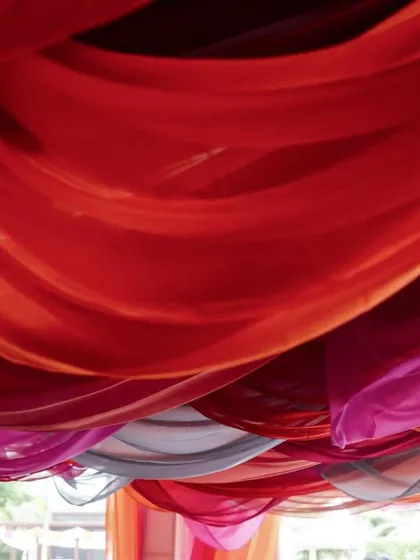 A close-up of the layered, draped fabric ceiling, showing the rich textures and vibrant colors used to create the canopy.