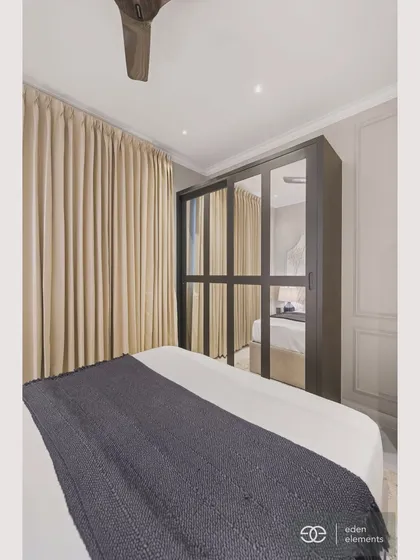 This view of the bedroom highlights the striking black wardrobe with mirrored fronts. The reflection adds depth and light to the space, demonstrating a clever blend of function and modern luxury.