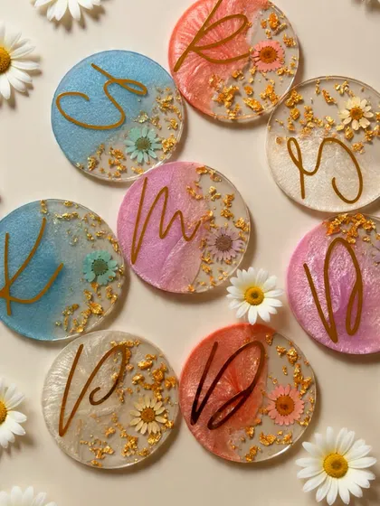 A close-up of my custom handmade resin coasters. Each piece is one-of-a-kind, featuring delicate dried flowers, gold leaf, and personalized initials, adding an artistic touch to any home.