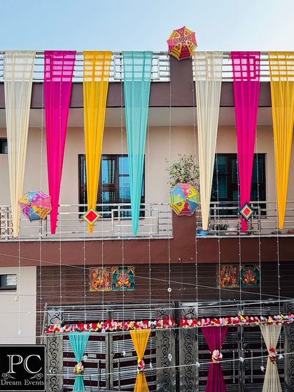 A full view of a house decorated for a wedding. We used long, flowing drapes in multiple bright colors, along with decorative umbrellas and hangings, to cover the entire facade of the building.