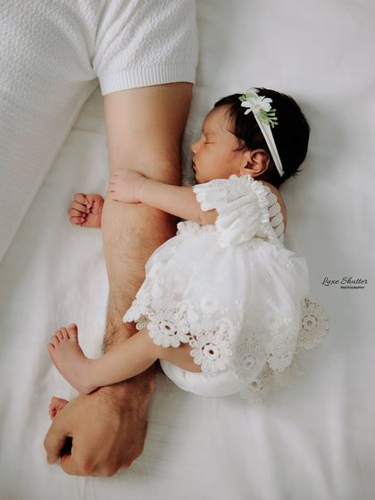 A unique and touching pose showing just how small the baby is, safely cuddling against her father's arm.