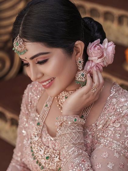 A close-up of the bride, her smile radiant. The makeup features soft pink tones and a beautiful rose in her hair.