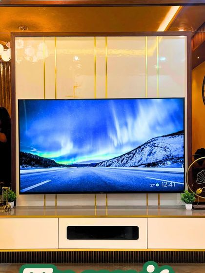 This TV unit design is all about glamour, with a large mirror-paneled backdrop, gold-finished accents, and a sleek white console. It's a statement piece for any modern living room.