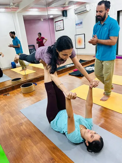 With my guidance, two students work together in a supported plank pose. This builds strength in the flyer and stability in the base, fostering teamwork.