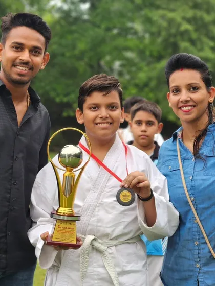 Another happy family celebrating their son's achievement. He holds a trophy and a medal, symbols of his hard work.