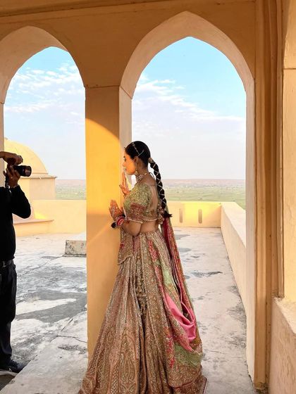 A behind the scenes shot of a bride with a unique, ribbon wrapped braid during her photoshoot.