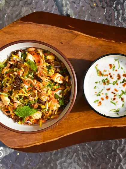 Another look at our delicious Nizami Tarkari Pulao, served with a side of cooling raita. This dish is a wholesome and aromatic choice for any meal.