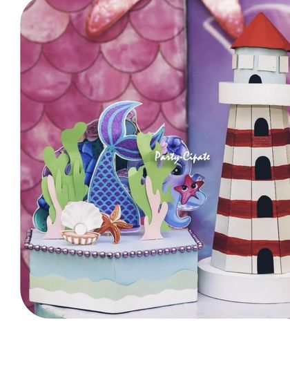 These custom-made props, a lighthouse and a mermaid-themed decorative box, added a unique and handcrafted touch to the party decor.
