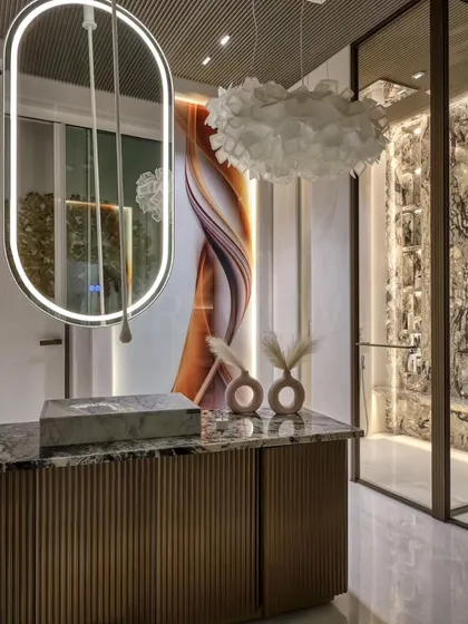 This luxurious bathroom design is a visual delight. The space features a floating vanity with fluted details, a dramatic backlit art panel, and a stunning marble feature wall, blending color, light, and sophistication to create a spa-like experience at home.