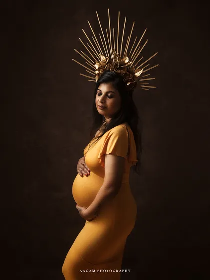 Motherhood is a royal affair. This portrait, with its golden gown and majestic crown, celebrates the queen that every mother-to-be is. It's a statement of strength, grace, and the miracle of creation.