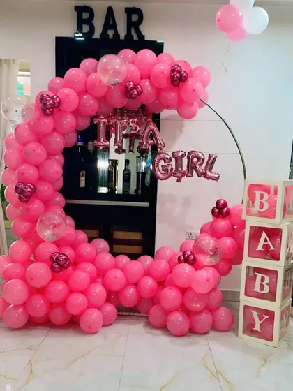 This is an "It's a Girl" announcement and welcome home setup. I used a half-moon balloon arch made entirely of pink balloons, with "BABY" display boxes and foil letters to celebrate the new arrival.