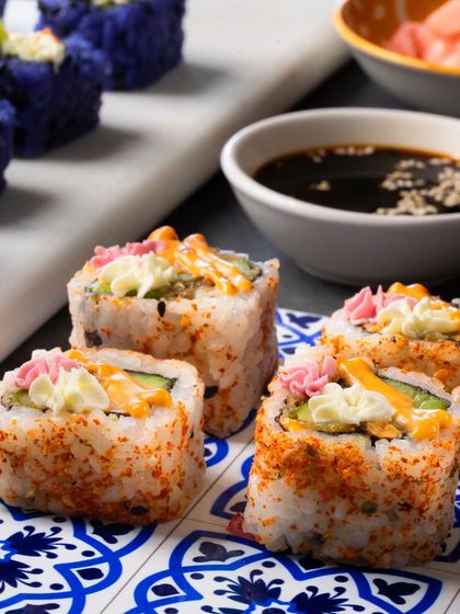 A platter of the Avocado Asparagus Tempura rolls, showing the spicy sauce and tempura flake topping.