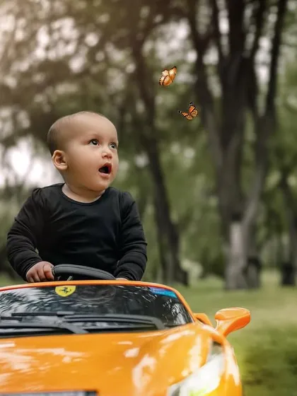 A moment of wonder as two butterflies fly past. This little boy is captivated by nature during his fun ride in a toy sports car.