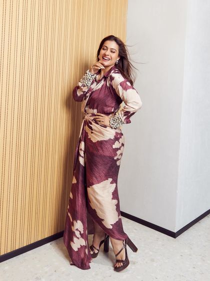 The full look of the printed wrap dress, showing off the high-heeled sandals and the joyful movement of the outfit.