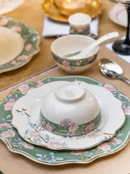 A beautifully stacked set of Vigneto's green and pink floral dinnerware. This shot clearly displays how the different pieces of the collection layer together to create a cohesive and elegant table setting.