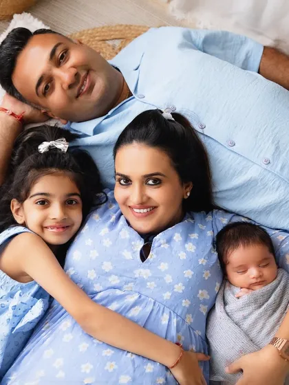 A perfect picture of a family of four. Lying together, this portrait captures a moment of peace and happiness with their newborn baby and proud big sister.