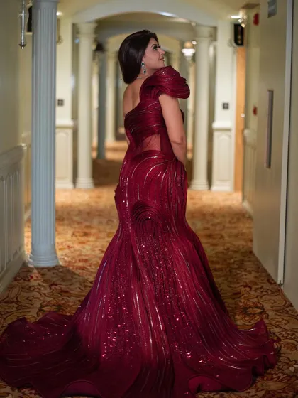 A beautiful back and side profile of the red sculpted gown, highlighting its unique texture and the way it drapes into a stunning train.
