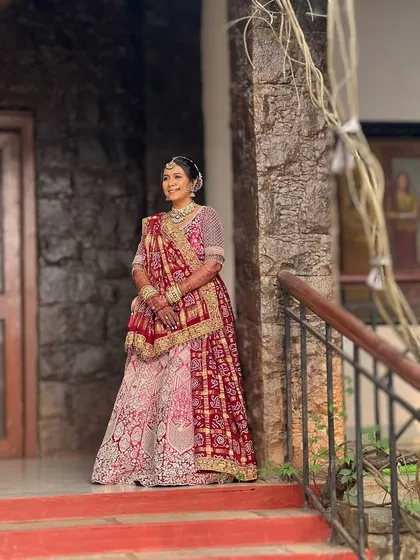 A full-length view of this bride's stunning traditional lehenga. The makeup and hair are styled to create a cohesive and elegant look that feels both grand and personal.