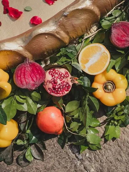 A flat lay of colorful fruits and vegetables, including pomegranates, bell peppers, and dragon fruit, used as decor for the 'La Tomatina' theme. This showcases the beauty of edible decorations.