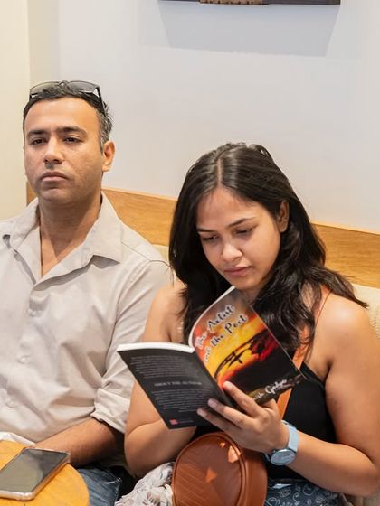 A reader engrossed in her newly acquired copy of "The Artist and the Poet" during the event itself.