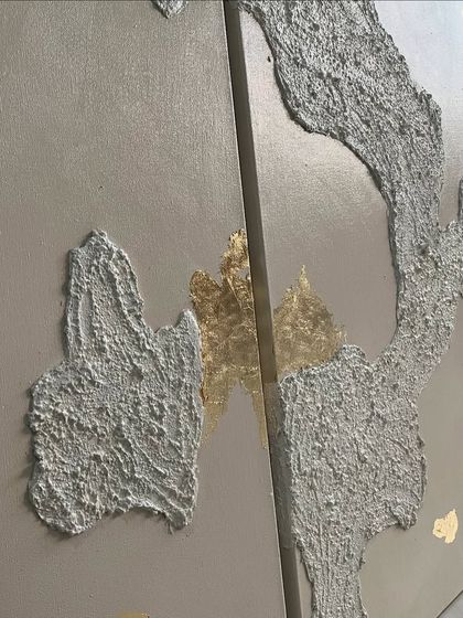 A detail shot where two of the panels meet, showing the interplay between the texture and the gold leaf accents across the canvases.
