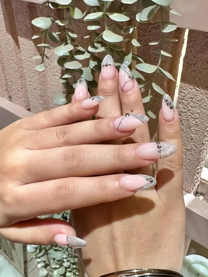 A glamorous set combining a sparkling glitter tip with delicate, abstract black line art for a modern and sophisticated design.