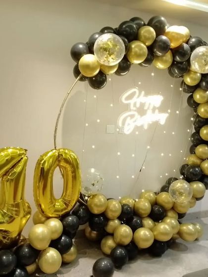 Celebrating a 40th birthday in style with a black and gold theme. This circular balloon arch includes large number balloons and a neon sign.