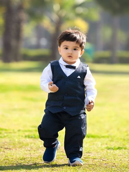 A toddler walks confidently across the grass during his outdoor first birthday photoshoot.