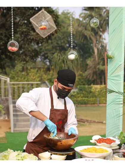A chef prepares a salad at a live station during a sunny outdoor brunch. We offer fresh, healthy options like custom salads to complement our more indulgent offerings.