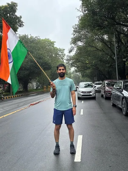 A runner holding the flag high on a Delhi road. We run with the spirit of India in our hearts.