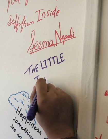 A volunteer writes on our "Happiness Wall" at the Mumbai office. Our team bonding meets are about connection and leaving a piece of our happiness behind.