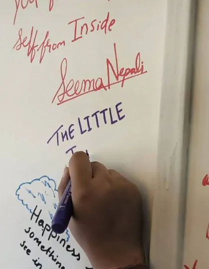 A volunteer writes on our "Happiness Wall" at the Mumbai office. Our team bonding meets are about connection and leaving a piece of our happiness behind.