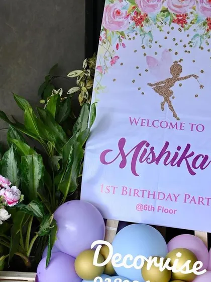 A clear shot of the welcome sign and decor, showing the combination of the custom printed easel, fresh flowers, and balloons that greet guests upon arrival.