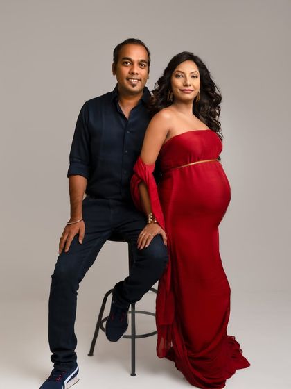 A stylish and confident couple's portrait. The bold red dress and their relaxed poses create a modern and powerful image.