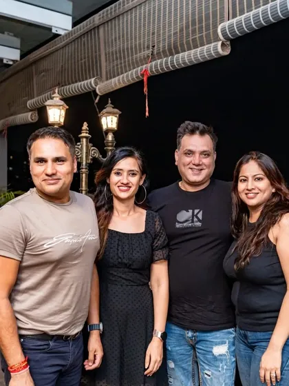 Friends enjoying a night out on the rooftop. The city lights in the background add to the ambiance.