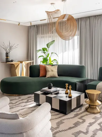 A wider view of the Evelyn living room, showing how the custom green sofa anchors the space. The design balances bold furniture with a neutral color palette and ample natural light, creating a luxurious yet inviting atmosphere.